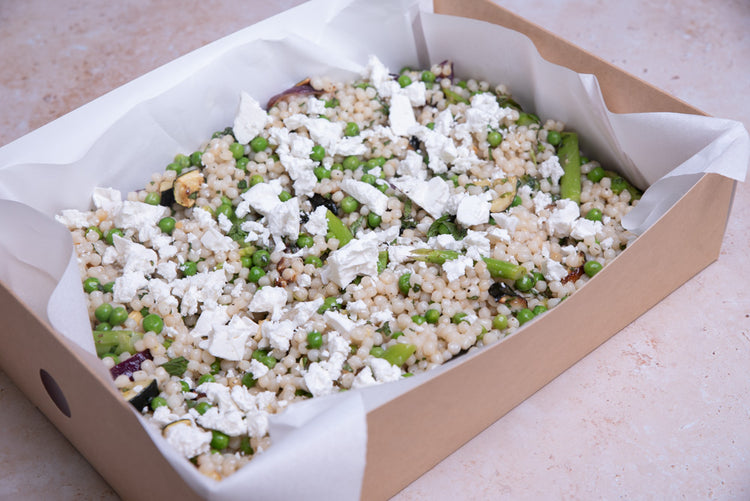 Sharing platter of vegan pearl couscous salad with peas, courgette, asparagus and mint